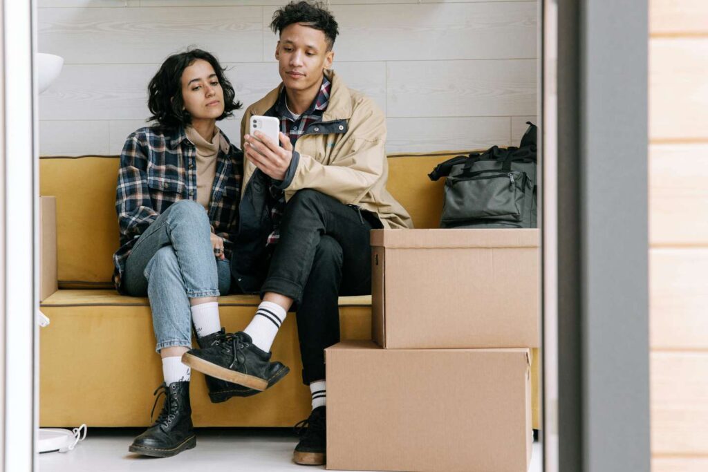 Young Couple Searching for a Rental on their Phone. They are packed and ready to go